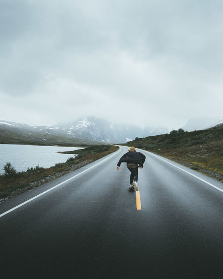 Woman skateboarding on road against sky during foggy weather