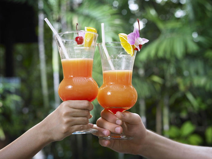 Cropped hands toasting drinks outdoors