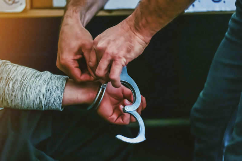 Close-up of man holding hand with handcuffs