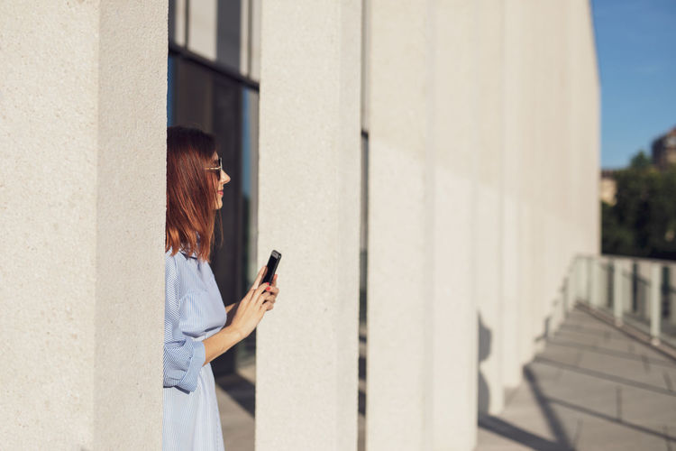 Woman using mobile phone while standing outdoors