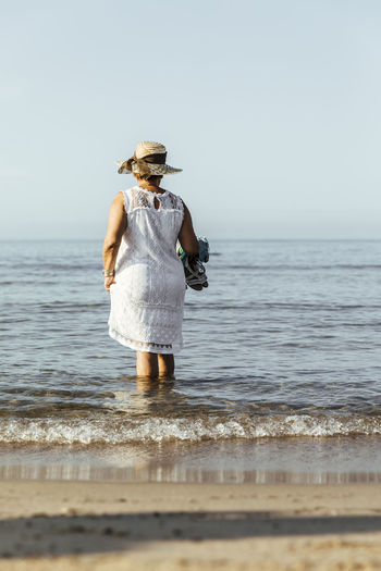Senior woman wading in the sea, el roc de sant gaieta, spain