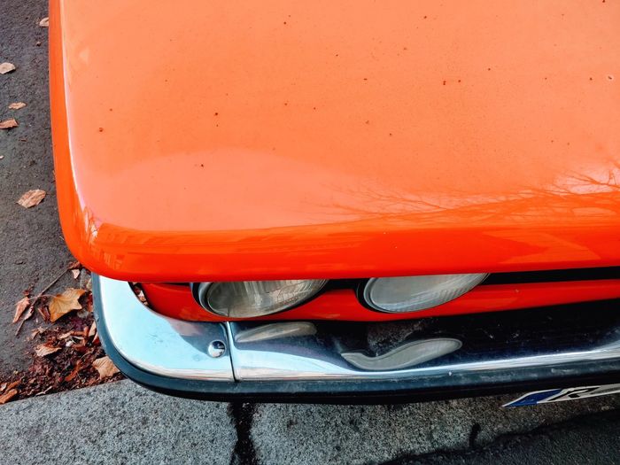 Cropped image of orange vintage car parked on road