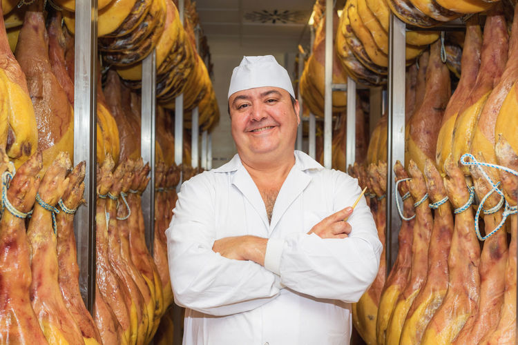 Portrait of smiling chef by meat standing in store