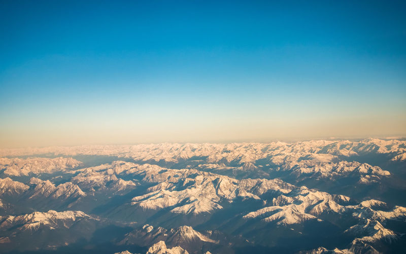 Aerial view of snowcapped mountains against clear sky