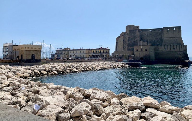 Buildings by sea against clear blue sky