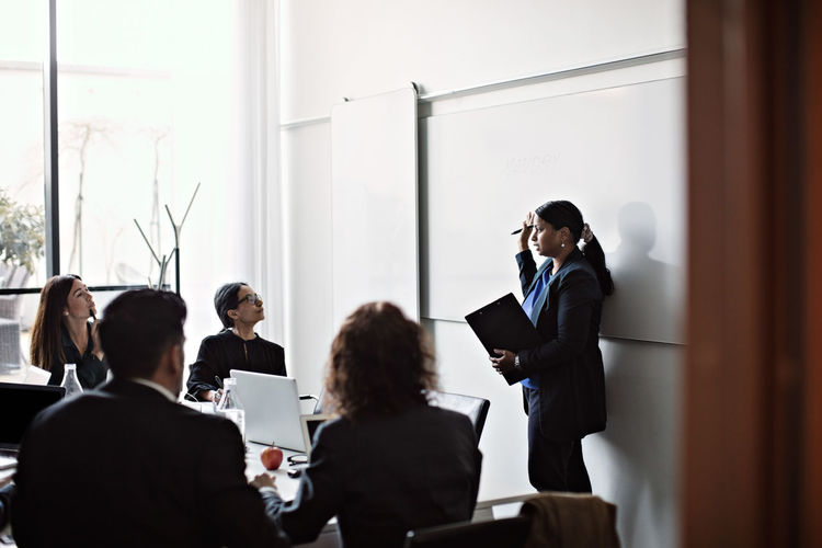 Businesswoman giving presentation to colleagues in office meeting