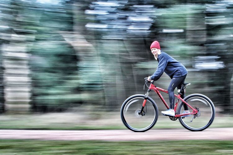 Blurred motion of man riding bicycle on road