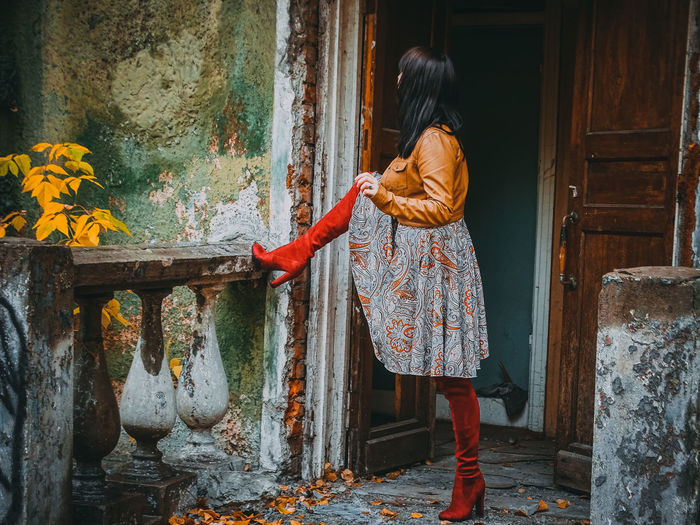 Full length of woman standing outside abandoned house