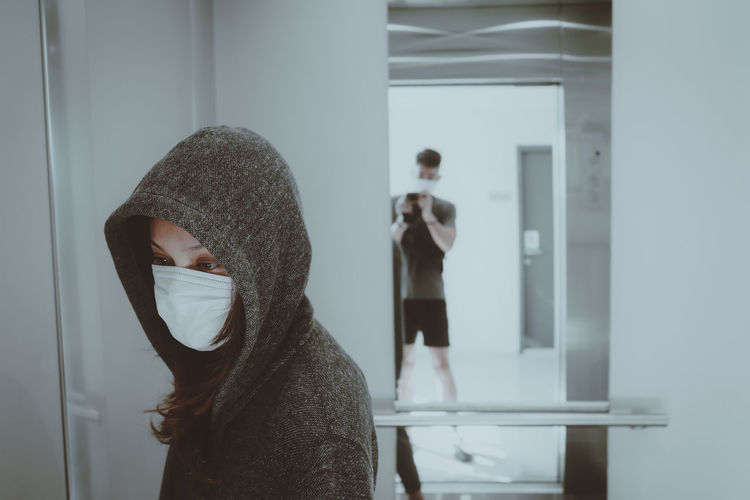 Candid, young woman wear hoody in lonely emotion and refection of photographer in the mirror
