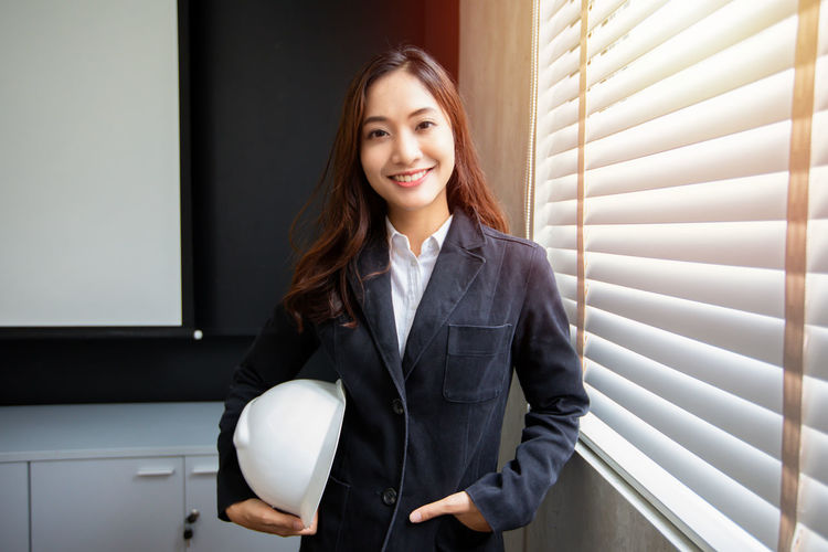 Portrait of young businesswoman standing against wall