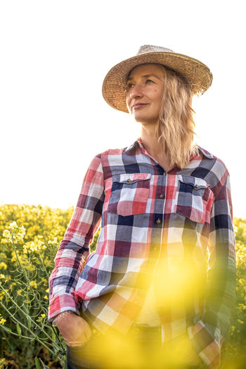 Portrait of a girl with hat and shirt in a rapeseed plantation