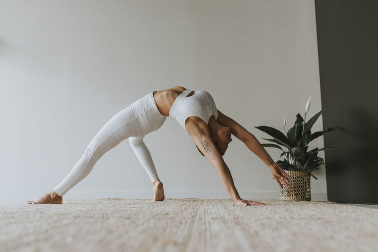 Flexible yogi practicing while bending over backwards at yoga studio