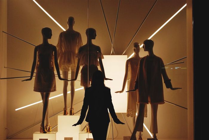 Rear view of woman standing against mannequins