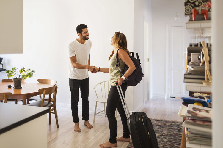 Happy man shaking hand with woman going for vacation