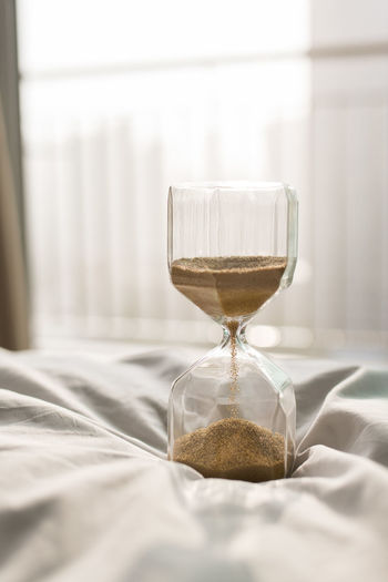 Close-up of hourglass on bed at home