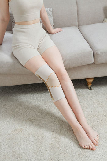 Low section of woman sitting on floor at home