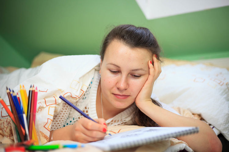 Young woman reading book on bed
