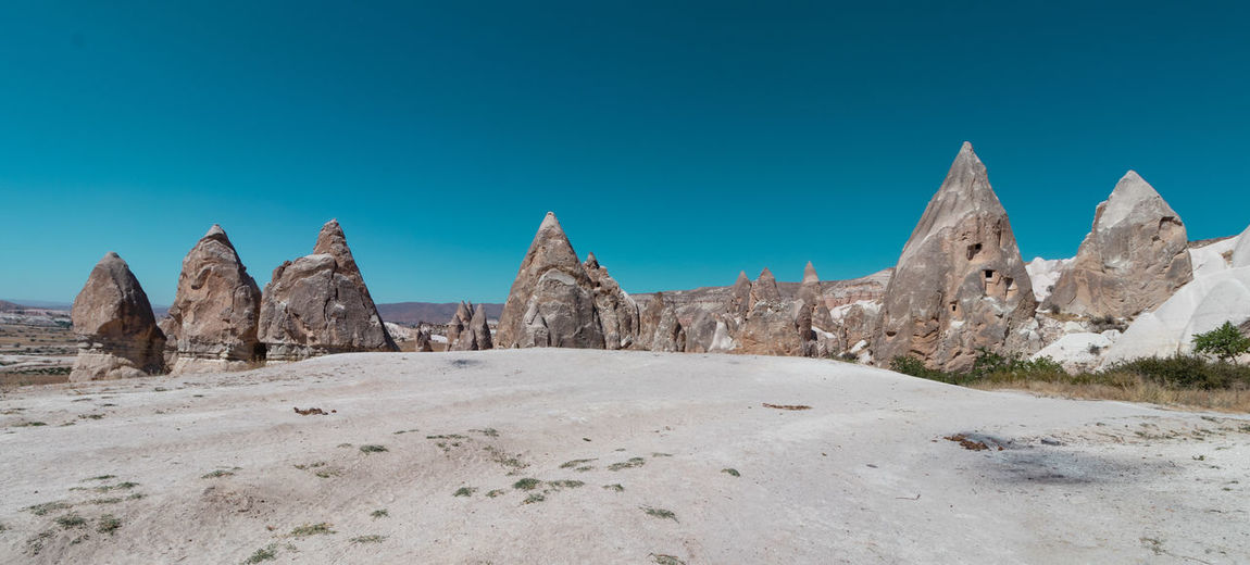 Panoramic view of arid landscape against clear blue sky