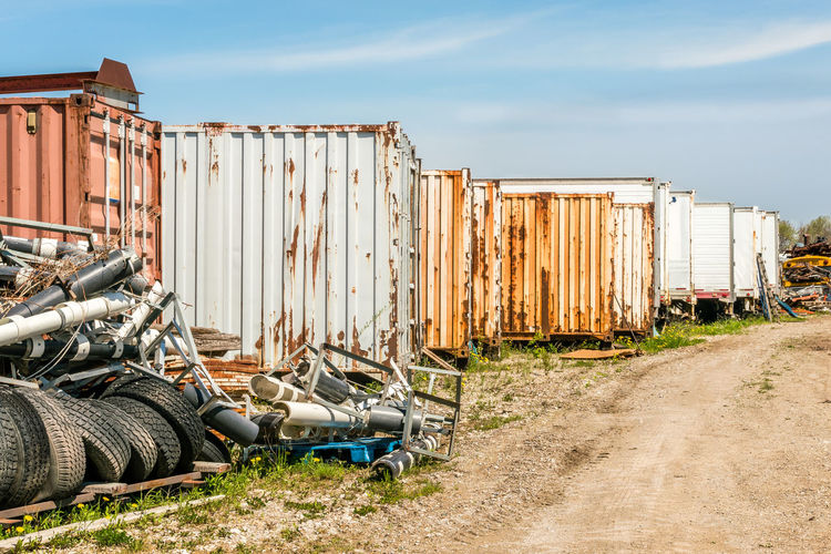 Stack of rusty metal fence on field against sky