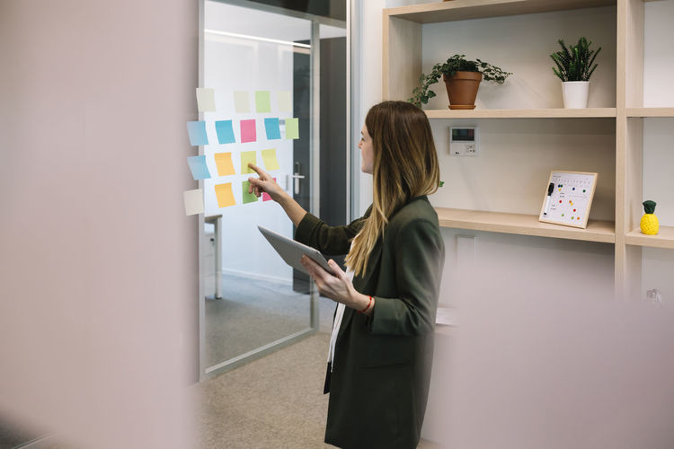 Female entrepreneur brainstorming while holding digital tablet at office