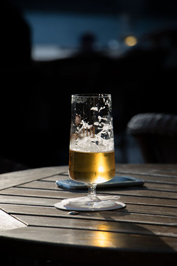 Beer in glass by mobile phone on table