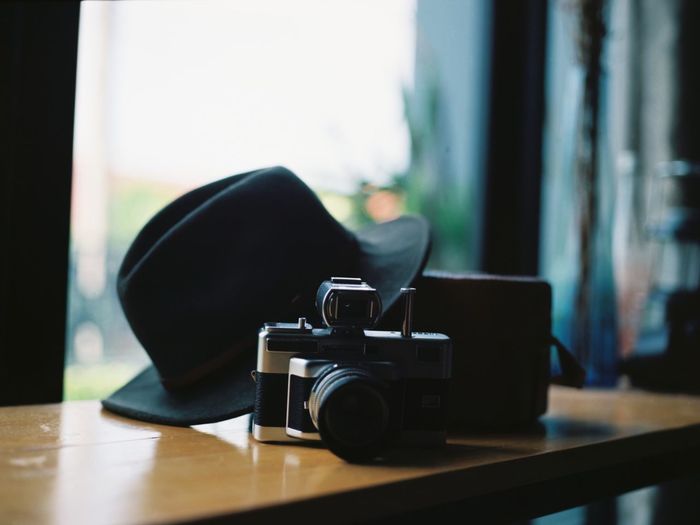 Close-up of camera an black hat on table at home