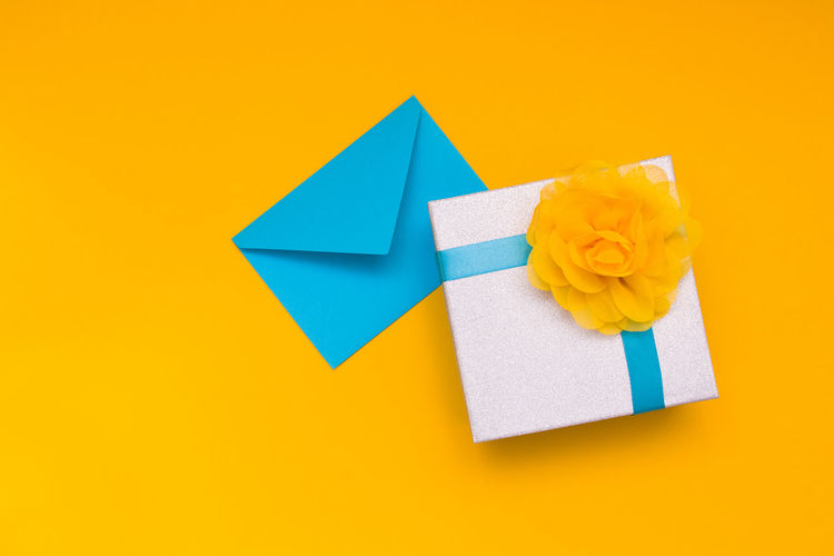 High angle view of box with envelop over yellow background