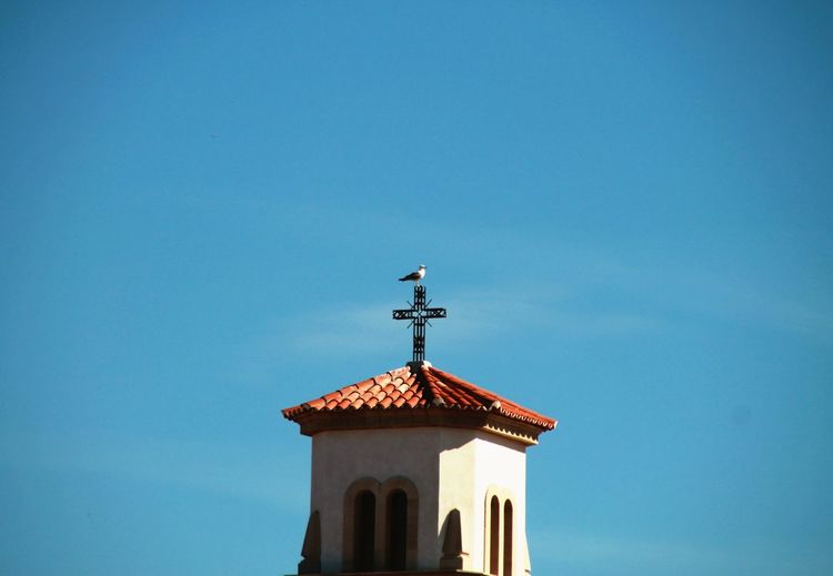 Low angle view of cross and building against sky