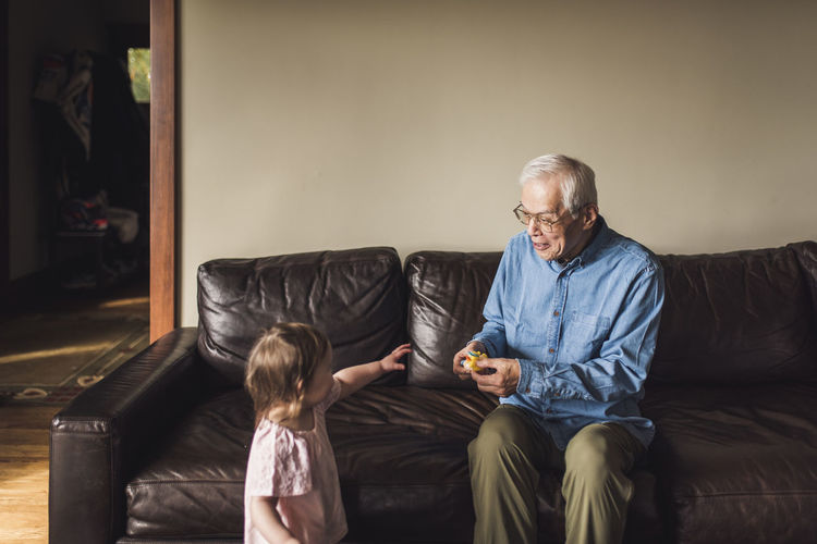 Grandfather and granddaughter playing in living room