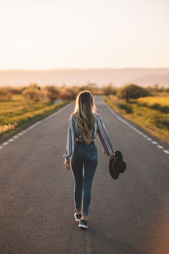 Rear view of woman walking on road