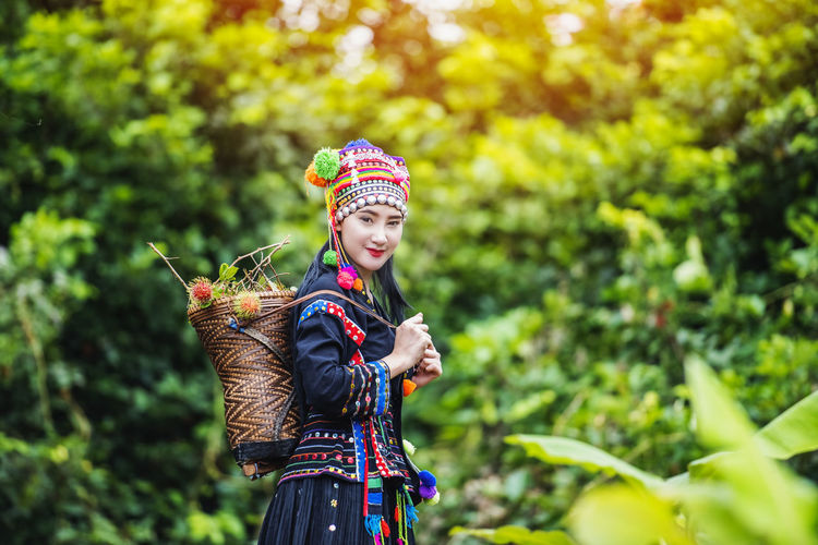 Portrait of smiling woman wearing traditional clothing standing against trees in forest