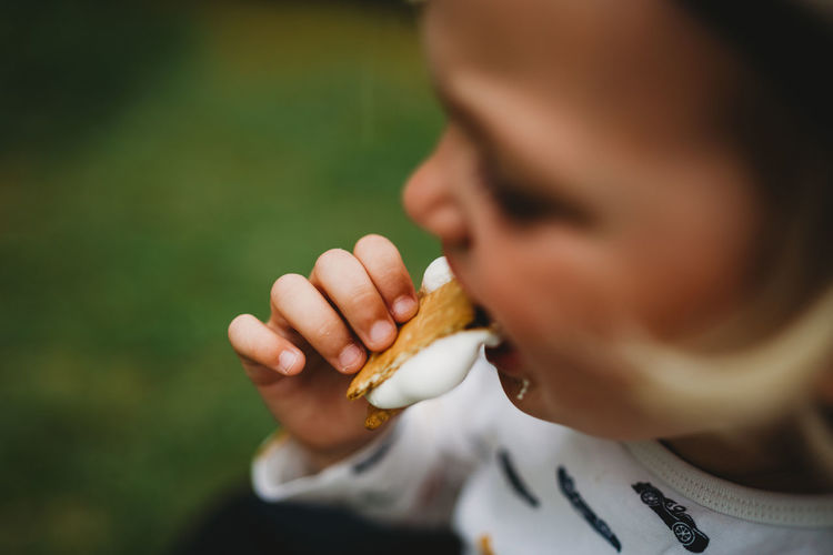 Close up detail of child's hand eating smores with melted marshmallow