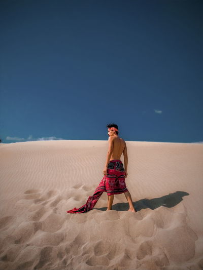 Full length of man on sand at beach against clear sky