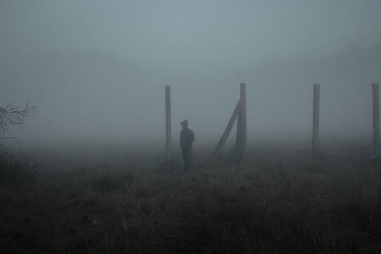 Man standing on field during foggy weather