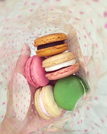 Double exposure of hand with fresh colorful macaroons in spotted bag
