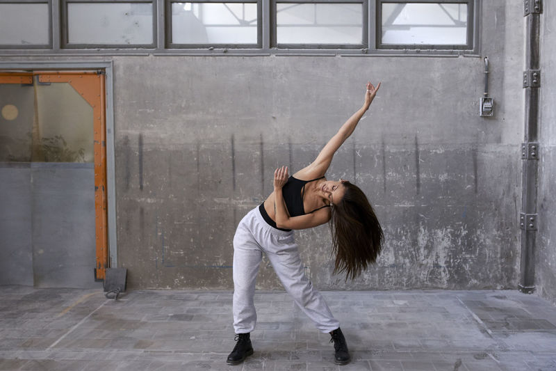 Female dancer practicing against wall in abandoned factory