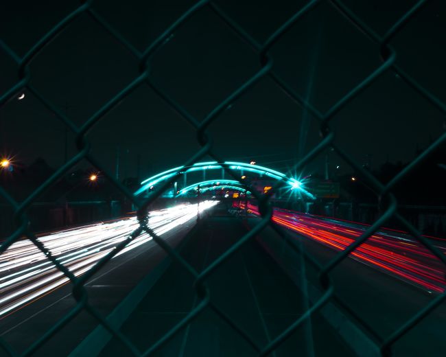 Light trails on chainlink fence at night