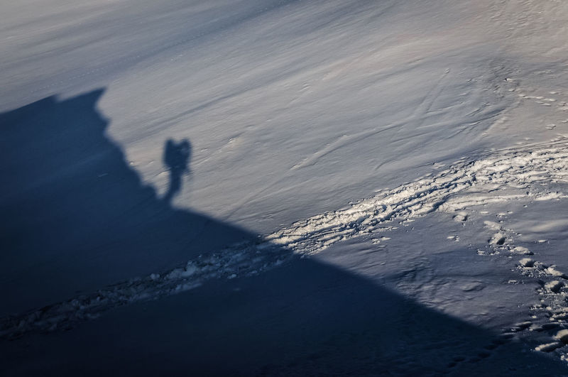 Shadow of people on snowcapped mountain by sea