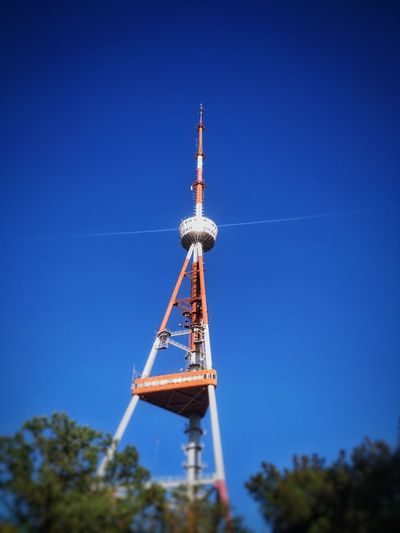 Low angle view of communications tower against clear blue sky