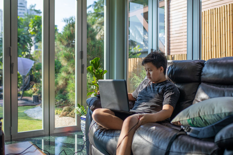Young woman using mobile phone while sitting on sofa at home