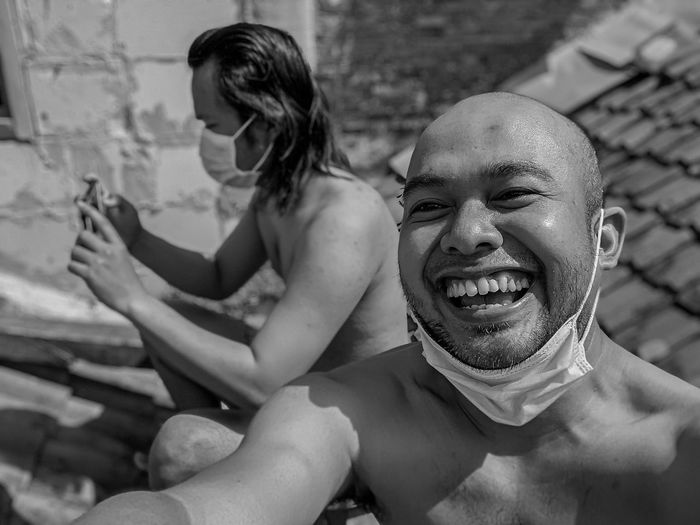 Portrait of a smiling young man while sunbathing at the roof in quarantine periode