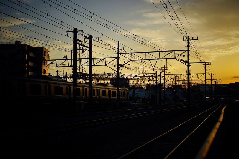Silhouette railway tracks against sky during sunset
