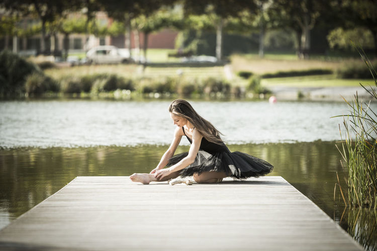 Woman in ballerina costume on pier over lake