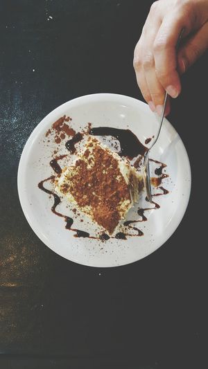Cropped hand of person slicing tiramisu in spoon
