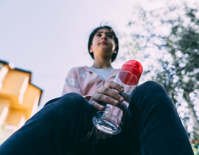 Low angle view of girl holding water bottle