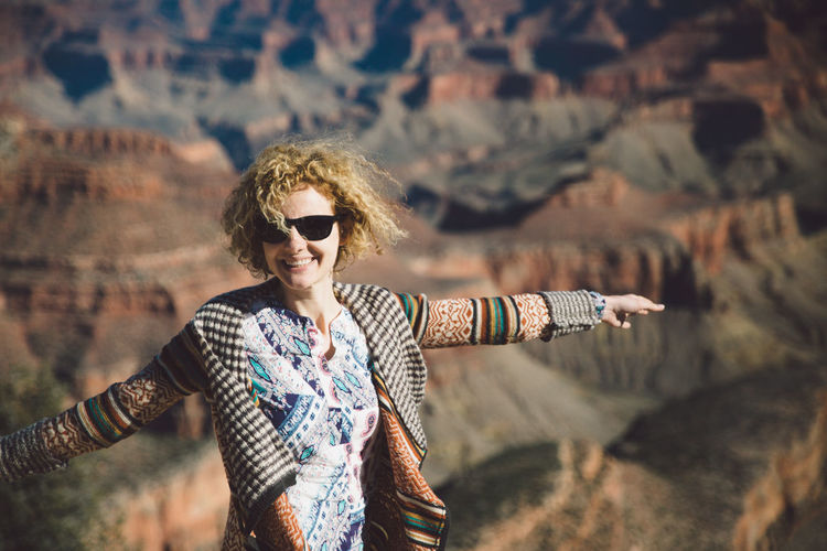 Portrait of smiling young woman standing with arms outstretched at grand canyon national park