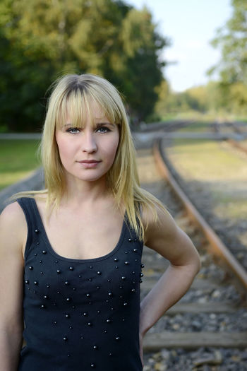 Portrait of woman standing on railroad track