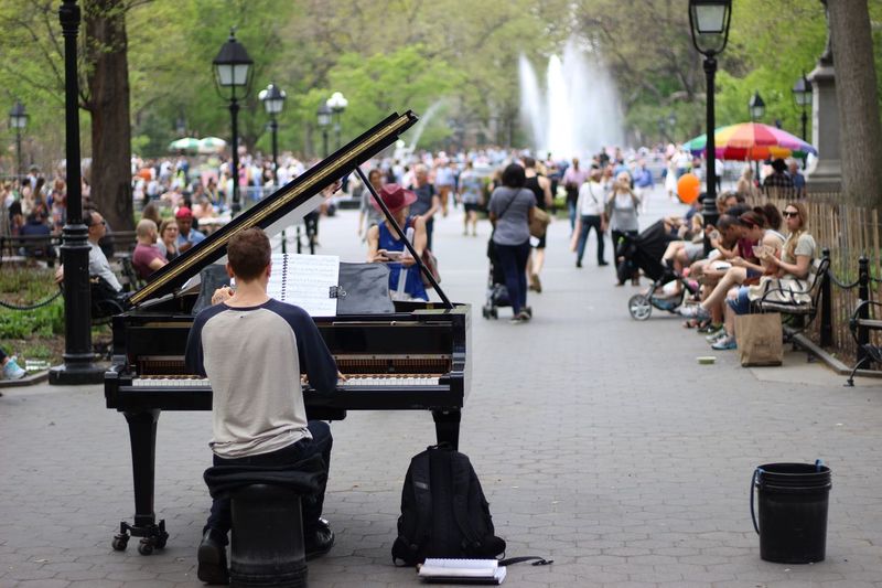Rear view of man playing piano on street at park