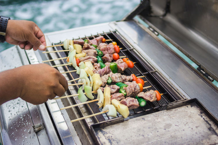 Cropped image of person preparing food on barbecue grill