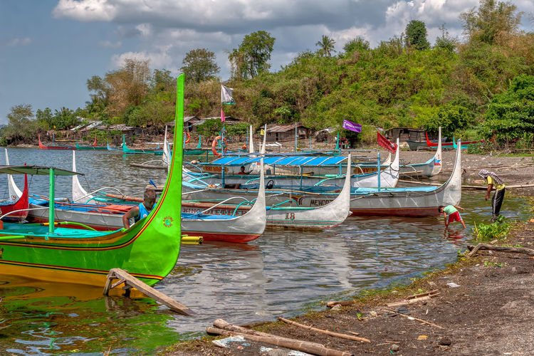 Boats moored on shore against sky